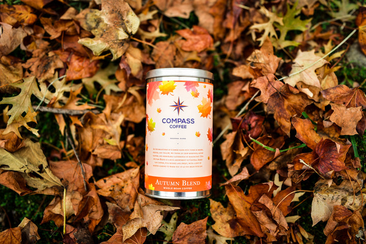 Compass Coffee Autumn Blend packaging surrounded by brown and red fall leaves.